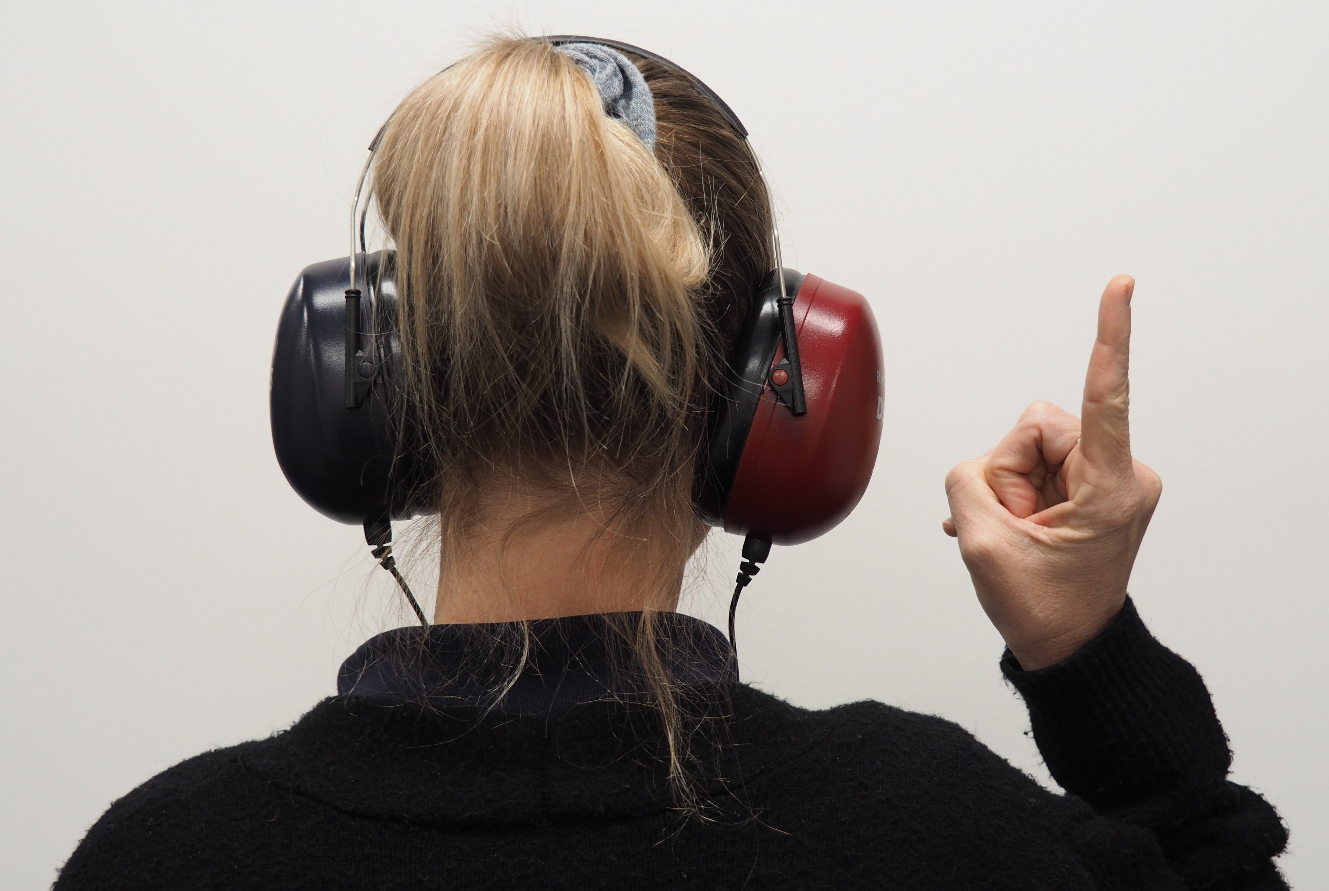 a woman wearing headphones raises one finger while taking a hearing test